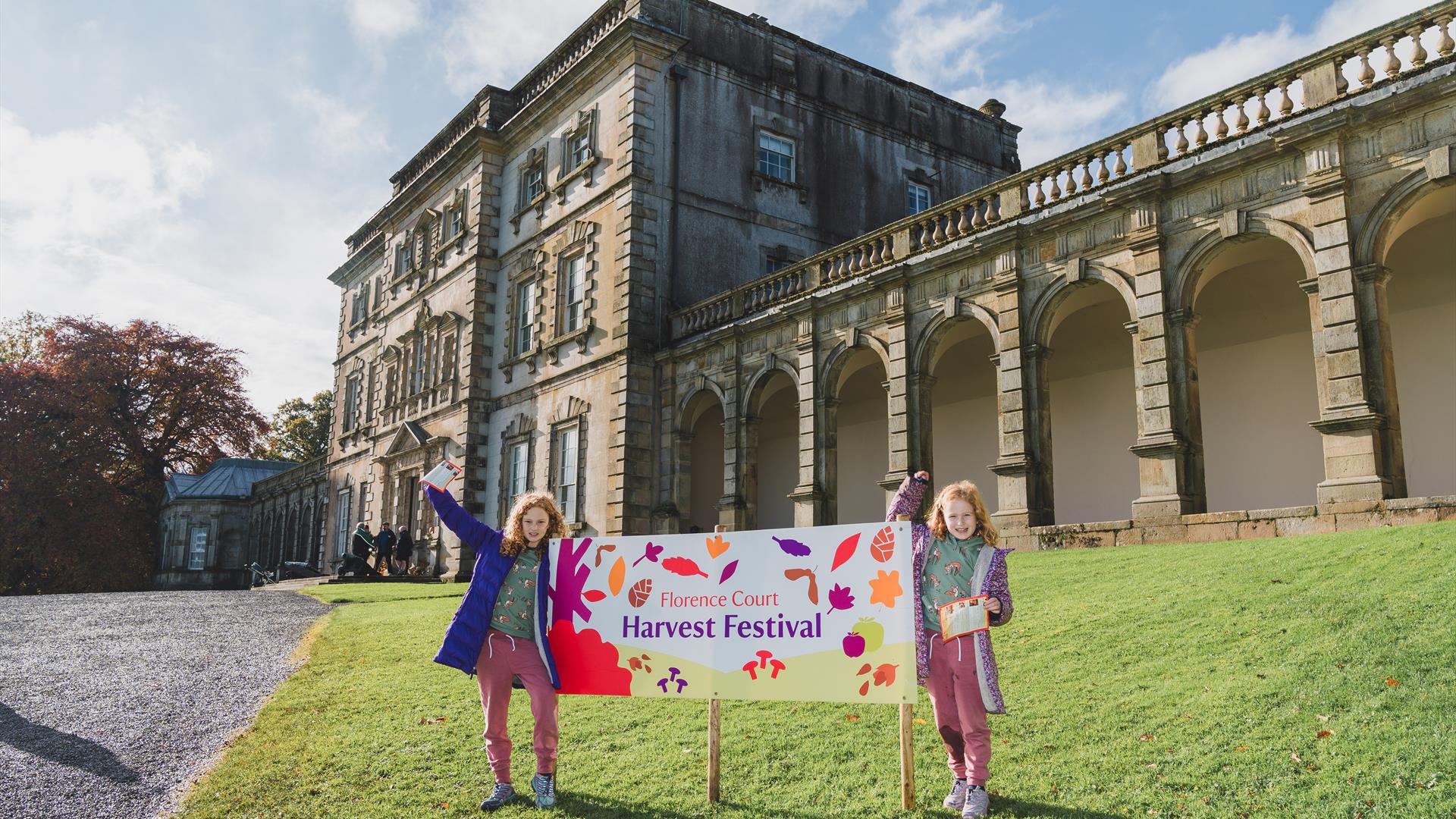 Two young visitors at the Harvest Festival sign outside Florence Court mansion