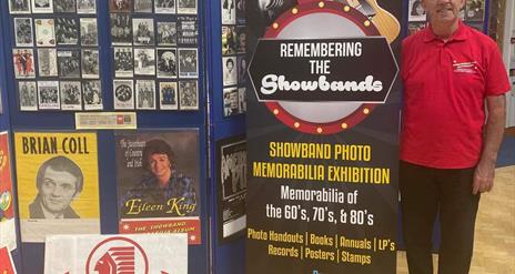 Photo of Philip D'arcy standing beside exhibition title