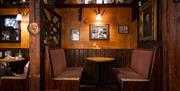 Cosy snug area with two facing seating benches below soft lighting with traditional Irish items displayed on shelving and on the wall.