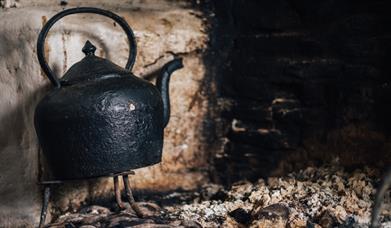 Image of a teapot on the hearth in a cottage at the Ulster American Folk Park